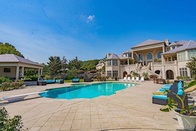 view of pool with a diving board, a patio area, and an outdoor hangout area