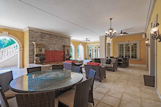 dining space featuring ornate columns, french doors, ceiling fan with notable chandelier, and ornamental molding