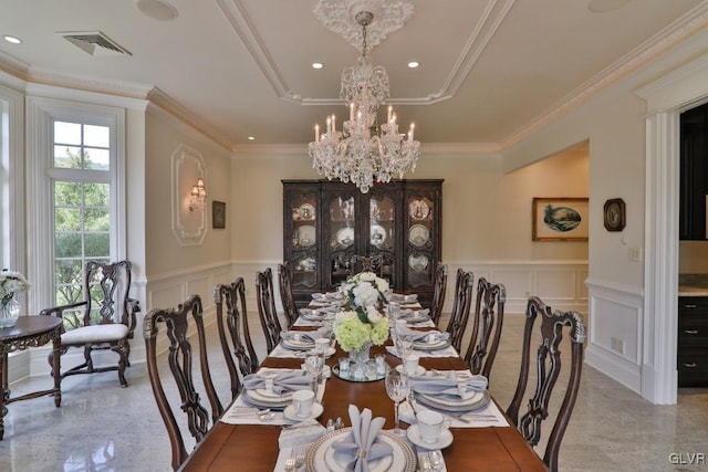 dining space with a raised ceiling, ornamental molding, and a notable chandelier