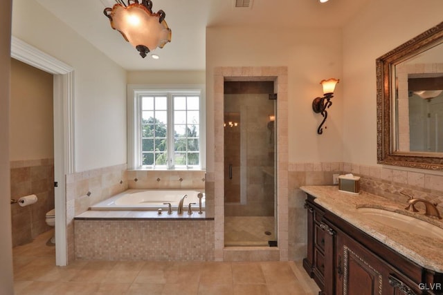 full bathroom featuring tile patterned floors, vanity, tile walls, shower with separate bathtub, and toilet