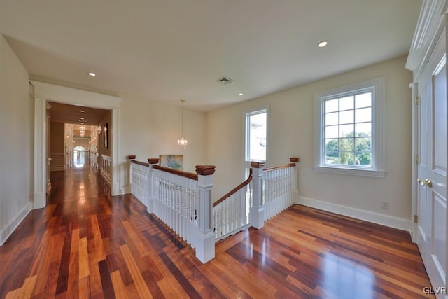 hall with dark hardwood / wood-style floors and an inviting chandelier