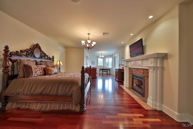 bedroom featuring a tile fireplace, dark hardwood / wood-style floors, and a notable chandelier