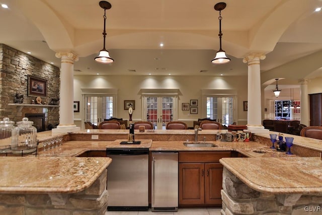 kitchen with stainless steel dishwasher, decorative light fixtures, sink, and decorative columns