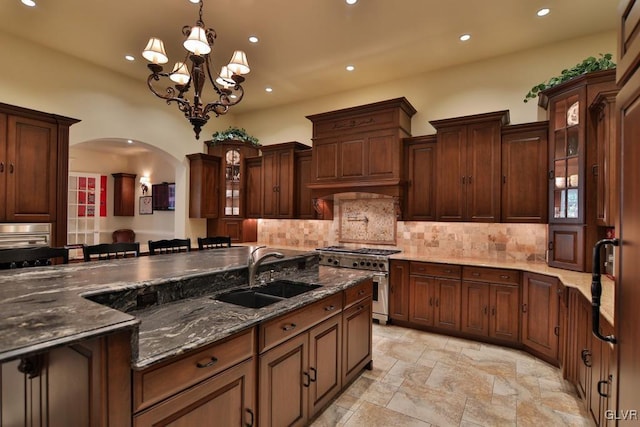 kitchen with stainless steel range, sink, a notable chandelier, decorative light fixtures, and a kitchen bar