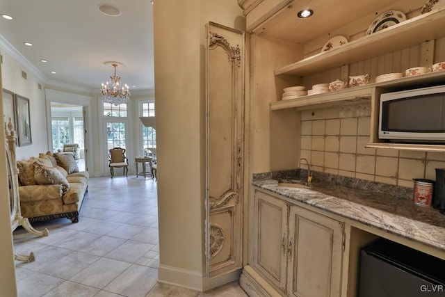 interior space featuring stone counters, tasteful backsplash, a chandelier, and sink