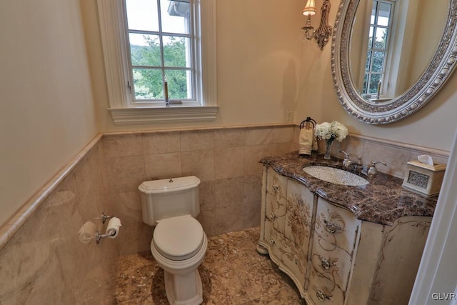 bathroom with vanity, toilet, and tile walls