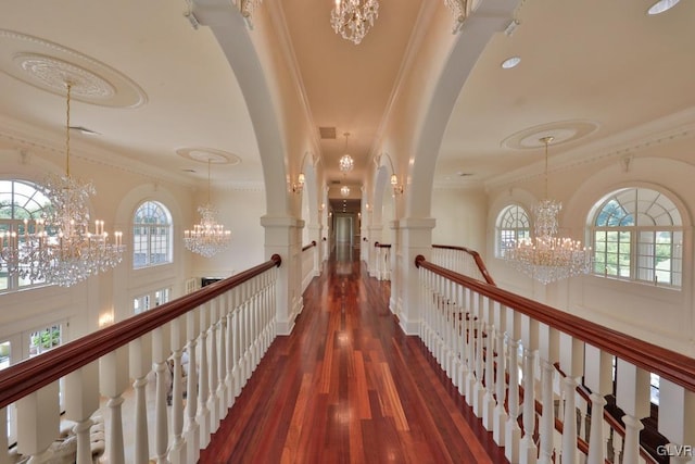 corridor with dark hardwood / wood-style floors, ornamental molding, and an inviting chandelier