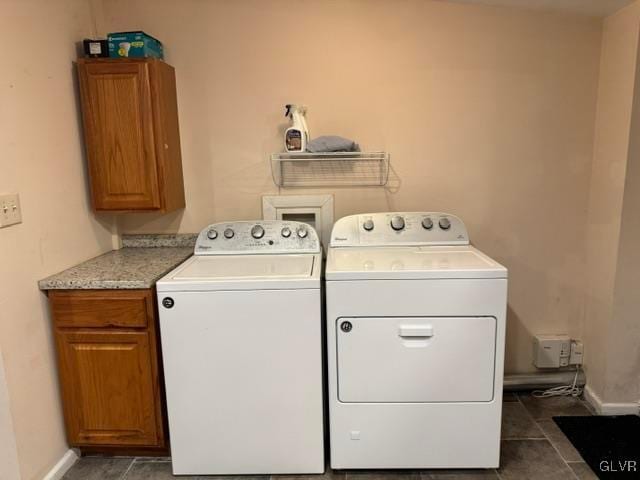 laundry room with baseboards, cabinet space, dark tile patterned floors, and washing machine and clothes dryer