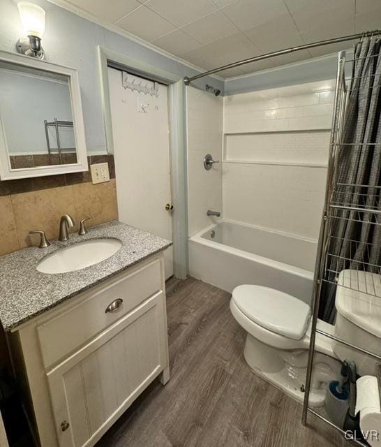 full bathroom with toilet, shower / tub combo, wood finished floors, vanity, and tasteful backsplash