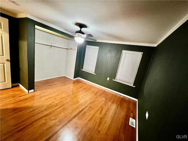 unfurnished bedroom with a closet, visible vents, baseboards, and wood finished floors