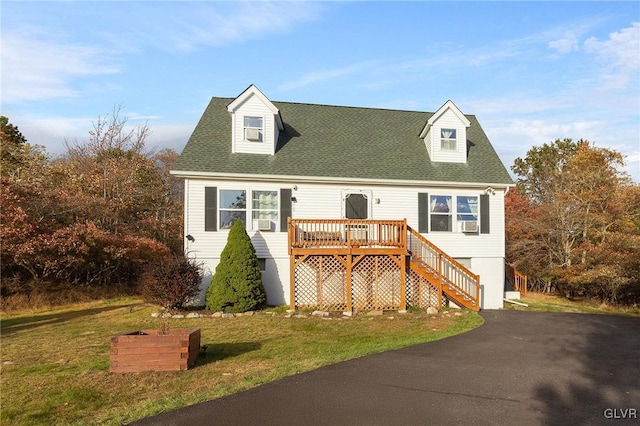 cape cod home with a wooden deck and a front lawn