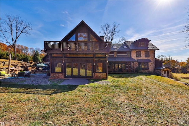 rear view of house featuring a wooden deck and a lawn