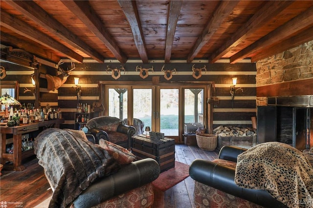 living room featuring beam ceiling, dark hardwood / wood-style flooring, wood walls, bar area, and a water view