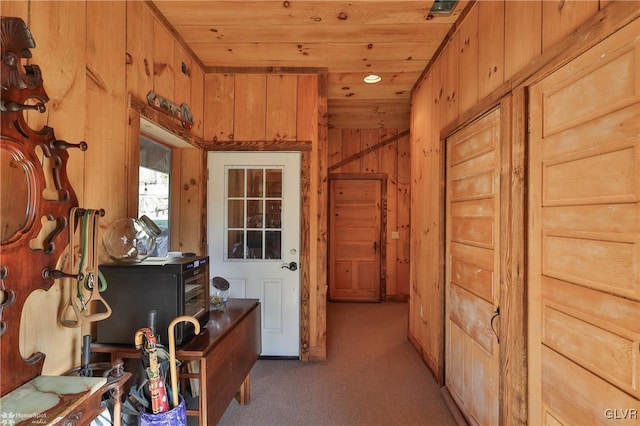 hallway with wooden walls, light colored carpet, and wooden ceiling