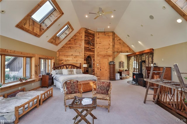 bedroom with light carpet, a wood stove, wooden walls, and a skylight