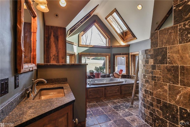 bathroom with vanity, lofted ceiling with skylight, and a tub