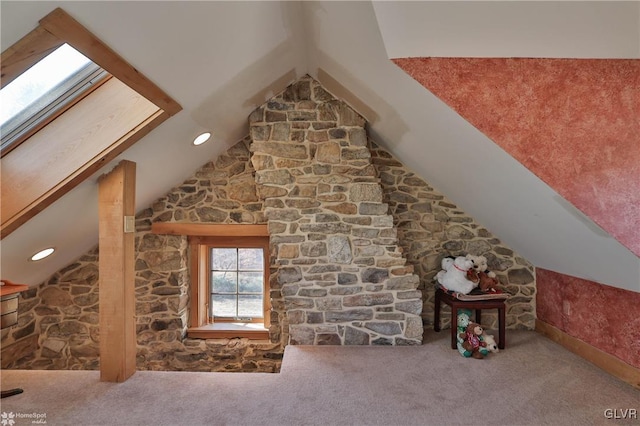 interior space featuring vaulted ceiling with skylight and carpet floors