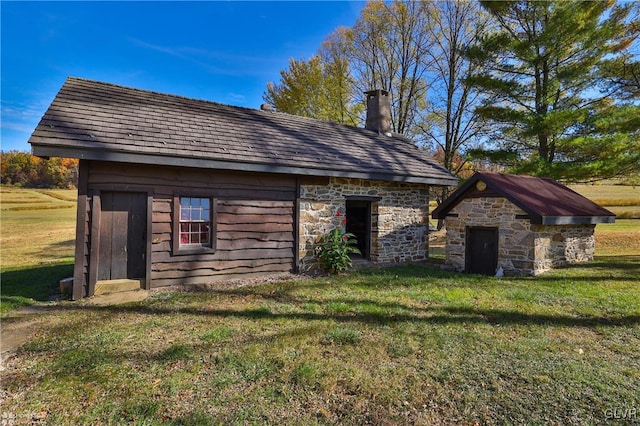 rear view of house with an outbuilding and a yard