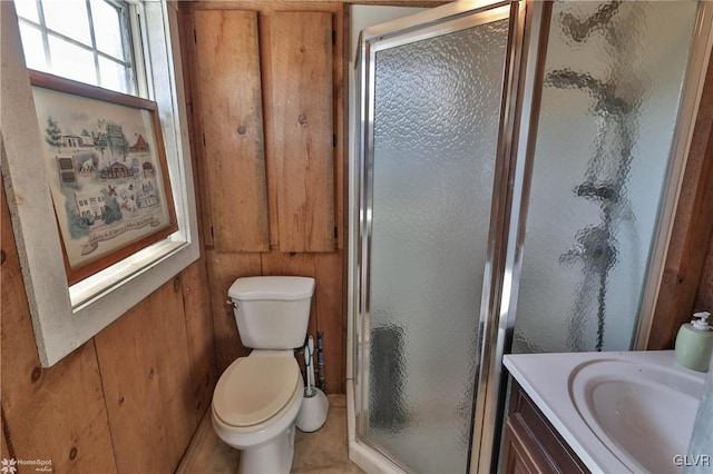 bathroom with vanity, toilet, wood walls, and walk in shower