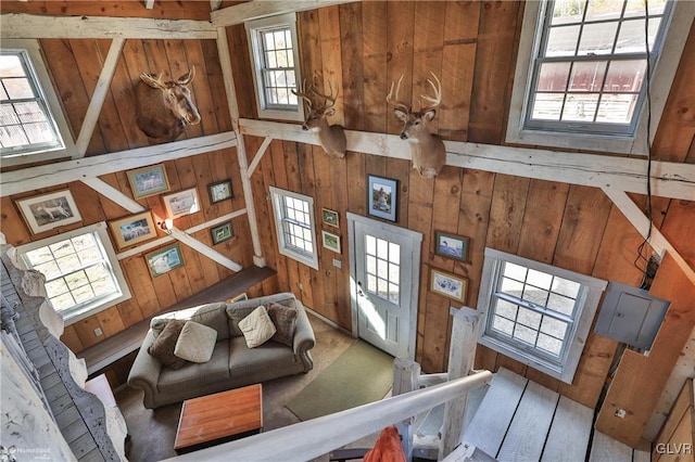 living room featuring wood walls, a towering ceiling, and a wealth of natural light