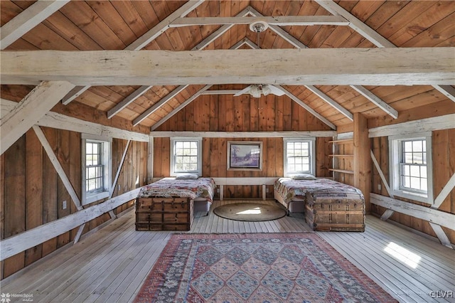 unfurnished bedroom featuring wooden ceiling, beamed ceiling, wood-type flooring, and wooden walls