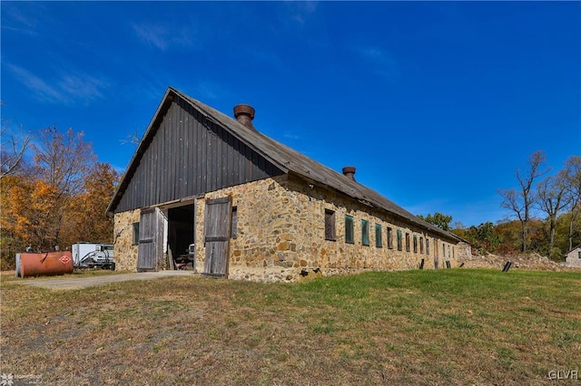 view of side of home featuring an outdoor structure and a lawn