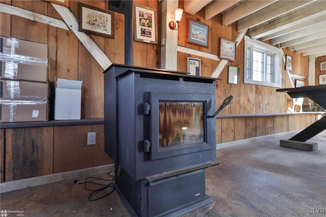 interior details featuring beam ceiling, a wood stove, and wood walls