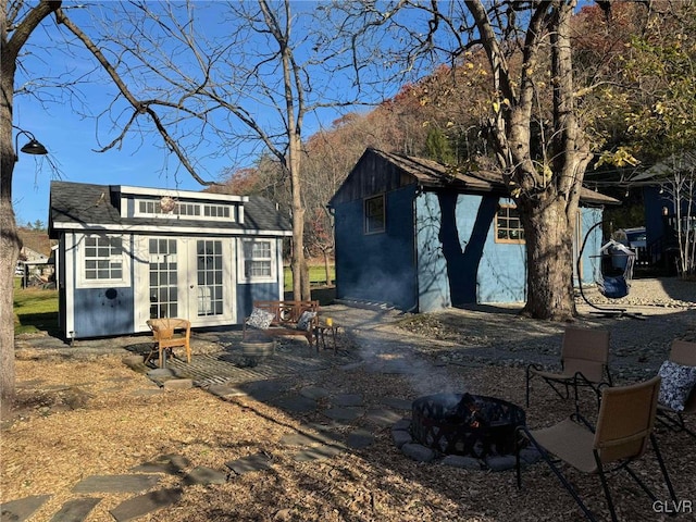 rear view of house featuring french doors, an outbuilding, and a fire pit