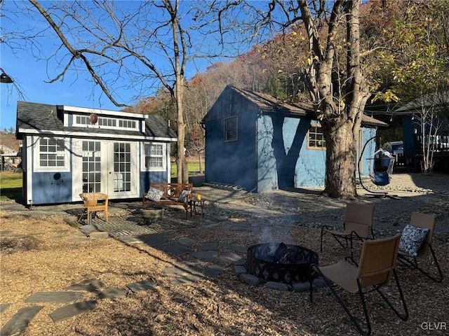 rear view of house with an outdoor fire pit, french doors, a mountain view, and an outbuilding