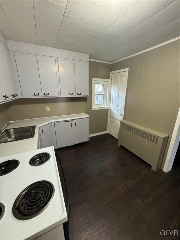 kitchen with white cabinets, radiator, white stove, dark hardwood / wood-style floors, and crown molding