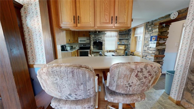 kitchen with stainless steel electric stove, a breakfast bar, and kitchen peninsula