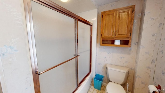 bathroom with toilet and shower / bath combination with glass door