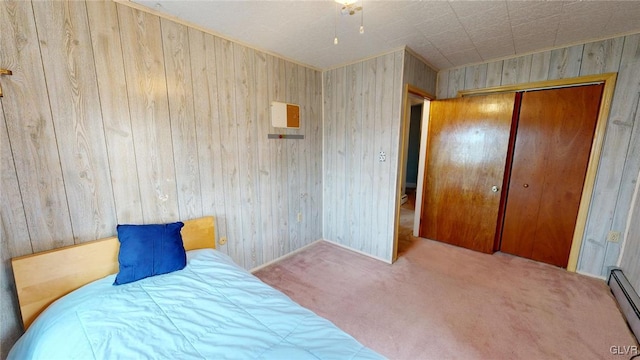 bedroom with a closet, a baseboard heating unit, wood walls, and carpet