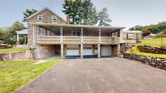 view of front of house featuring a sunroom, a front yard, and a garage