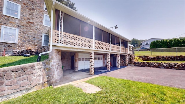 view of side of property featuring a lawn, a garage, and a sunroom