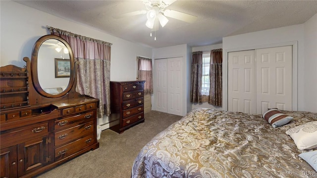 bedroom featuring multiple closets, light carpet, a textured ceiling, and ceiling fan