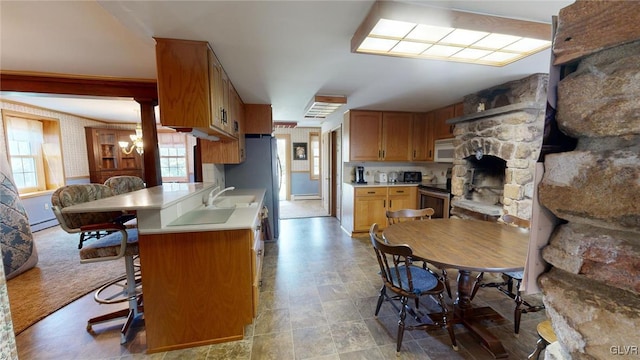 kitchen with a baseboard heating unit, stainless steel appliances, a wealth of natural light, and a breakfast bar area