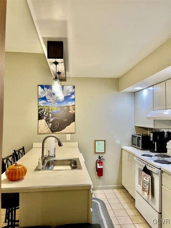 kitchen with white cabinetry, white range with electric cooktop, sink, light tile patterned floors, and a breakfast bar area