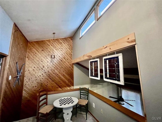 interior space featuring carpet flooring, wooden walls, and ceiling fan