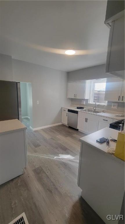 kitchen featuring white cabinetry, light hardwood / wood-style flooring, stainless steel dishwasher, and sink