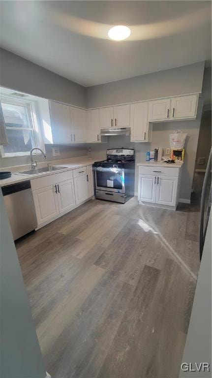 kitchen with white cabinetry, stainless steel appliances, sink, and light wood-type flooring