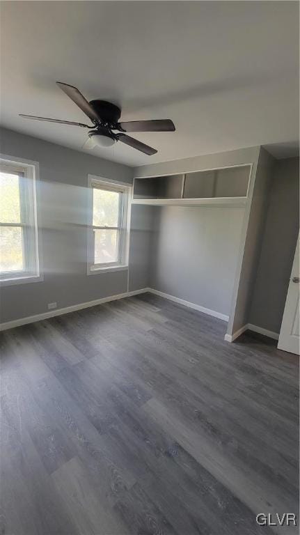 unfurnished bedroom with a closet, ceiling fan, multiple windows, and dark hardwood / wood-style floors