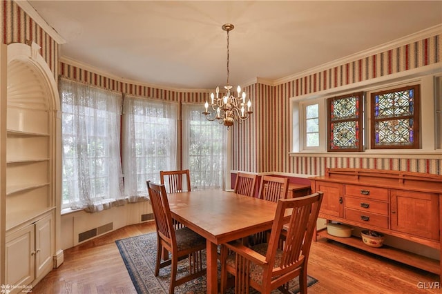 dining room featuring light hardwood / wood-style floors, a chandelier, and ornamental molding