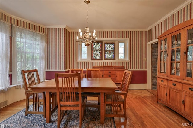 dining space with light wood-type flooring, plenty of natural light, a notable chandelier, and crown molding