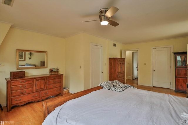 bedroom with light hardwood / wood-style floors, ceiling fan, and two closets