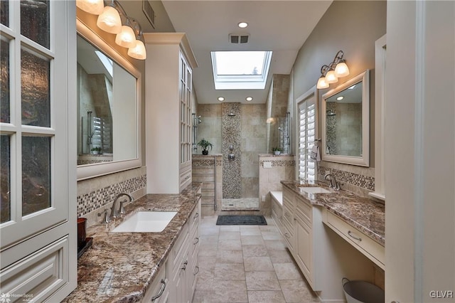 bathroom with a shower with door, tile patterned flooring, a skylight, vanity, and decorative backsplash