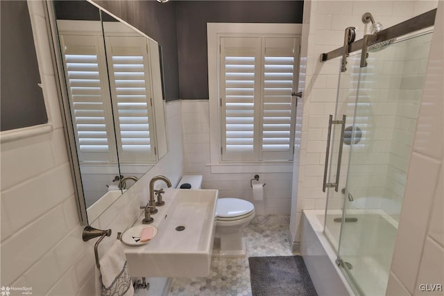 full bathroom featuring enclosed tub / shower combo, toilet, tile walls, tile patterned flooring, and sink