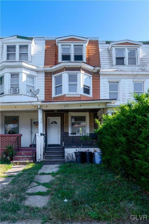 multi unit property with covered porch and a front yard