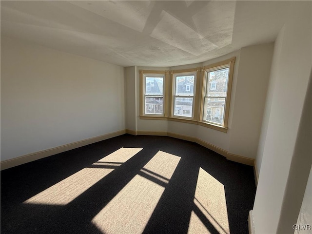 unfurnished room with dark carpet