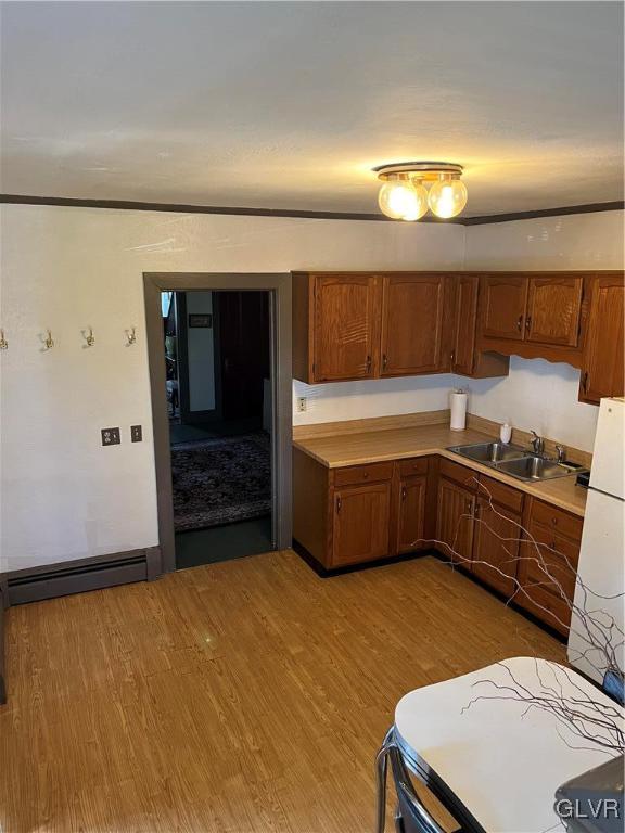 162 S Union St, Easton, PA 18042 - kitchen featuring a baseboard heating unit, wood finished floors, light countertops, and brown cabinetry